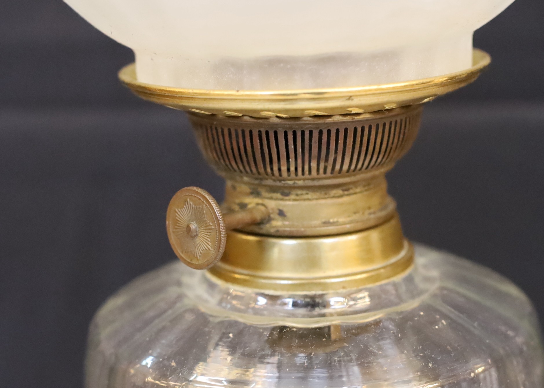 An Edwardian brass oil lamp with lobed glass reservoir, frosted globe and flue, height overall 74cm